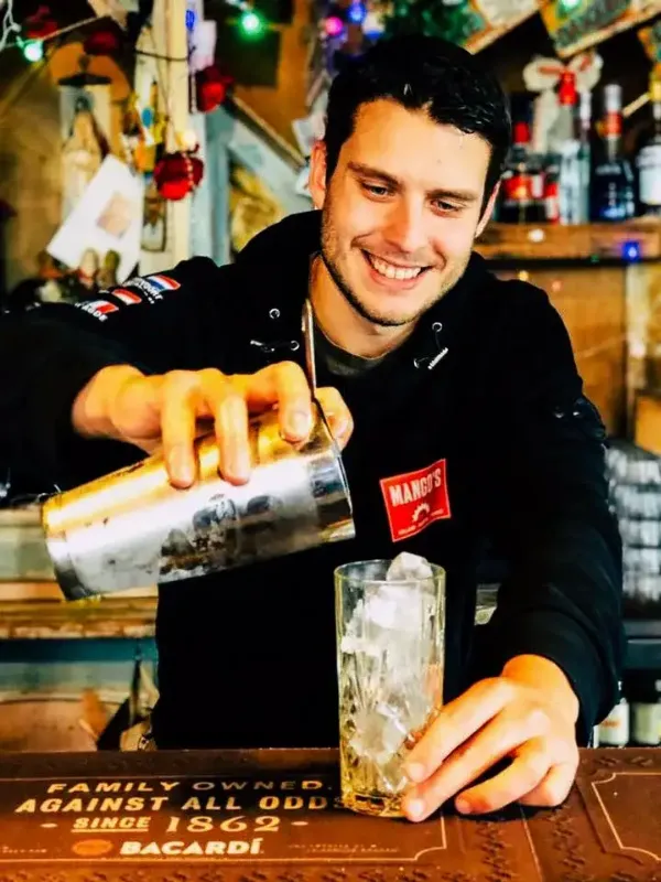 Barman schenkt cocktail in.
