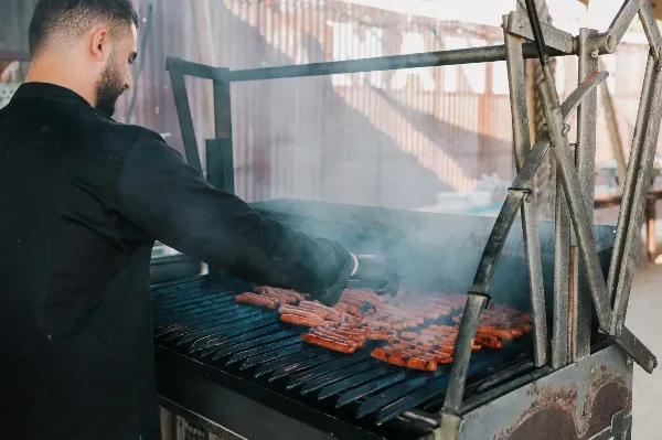 Kok bereidt vlees voor op de grill.