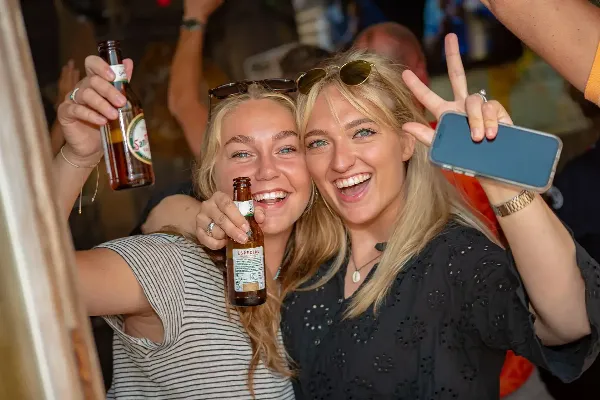 Twee meiden met een biertje, lachend.